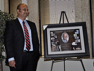 Dr. Karandikar standing in front of a plaque