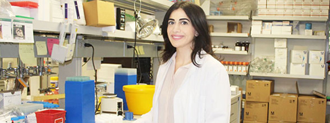 Farah Itani smiling in front of some lab equipment