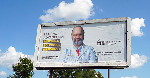 A billboard featuring Dr. Karandikar in front of a bright sky