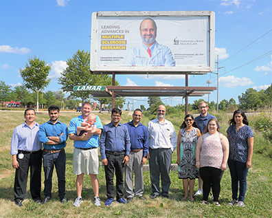 Several people in front of the billboard featuring Dr. Karandikar