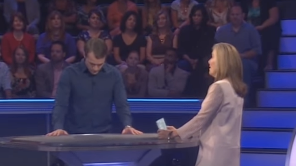 Andrew thinking while on the Who Wants to Be a Millionaire set in front of the host